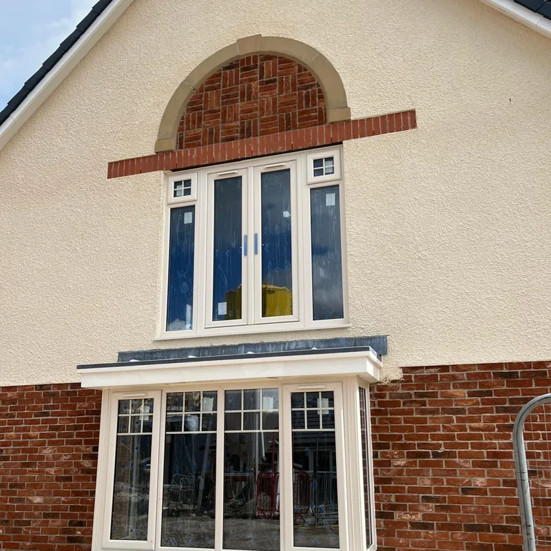 Arched panel of patterned brickwork above the windows on the gable of a new home.