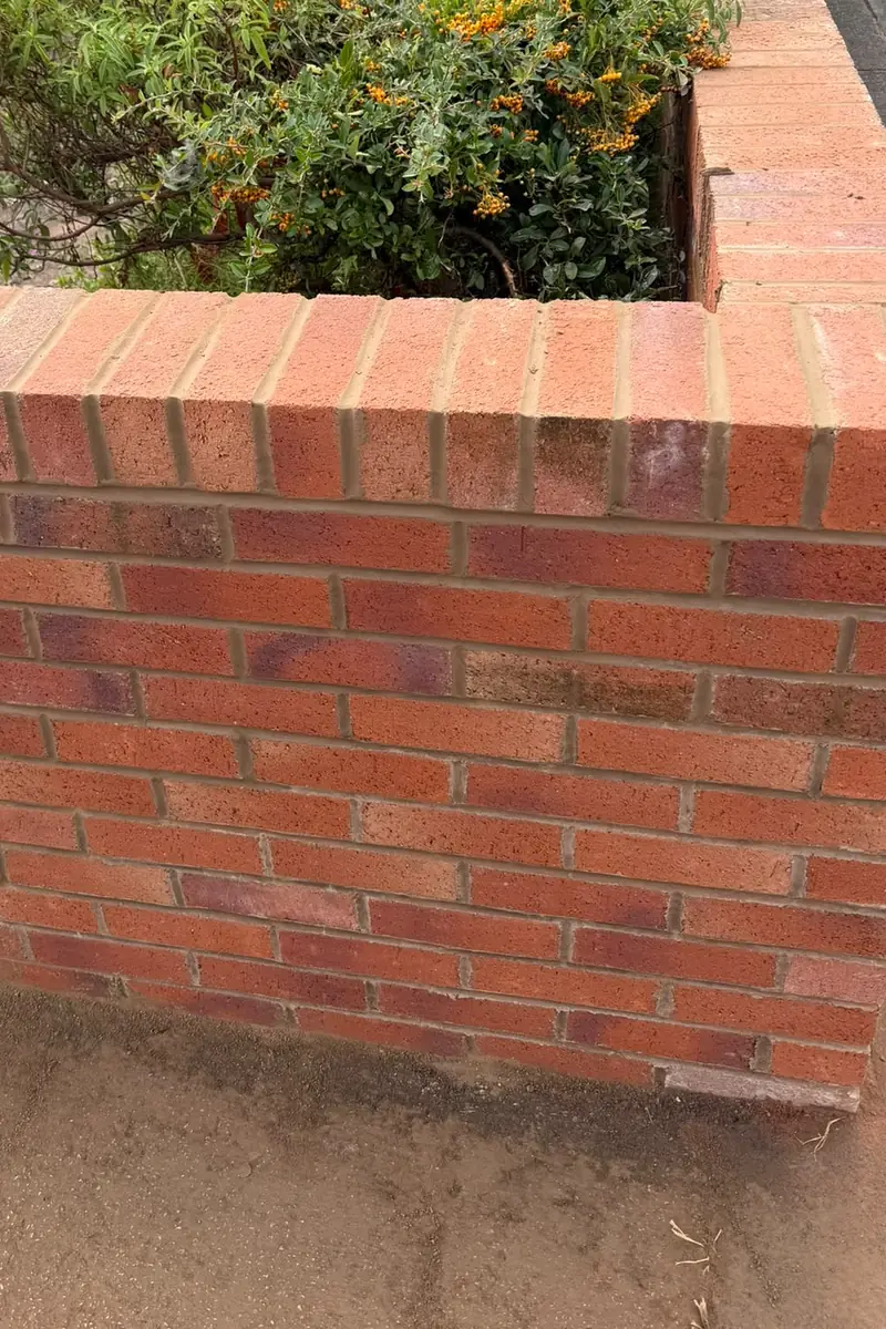 The rebuilt red brick front garden wall, finished with a brick-on-edge top course.