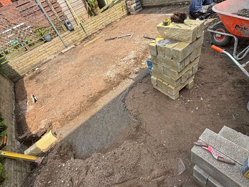 Garden area dug out during preparation, with stone walling materials stacked ready to use.