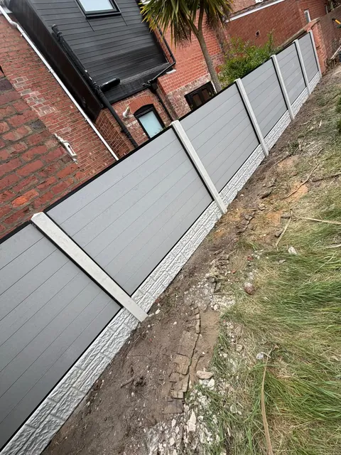 The grey fence seen at an angle from the other end of the garden.