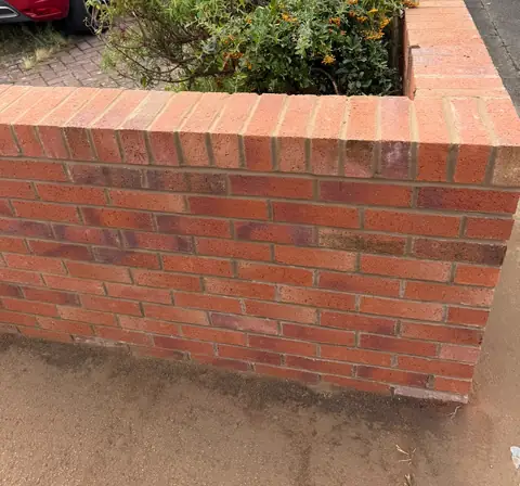 The rebuilt red brick front garden wall, finished with a brick-on-edge top course.