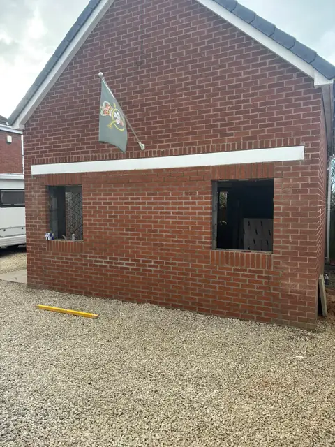 The same garage front bricked up in matching red brick, with two new window openings.