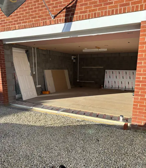 Inside a garage at the start of a conversion, with block walls and building materials stacked inside.