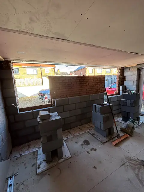 Inside the garage, with new blockwork being built across the former door opening.