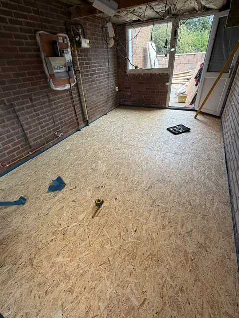 New floor boarding laid across the garage, with the brick walls still bare.