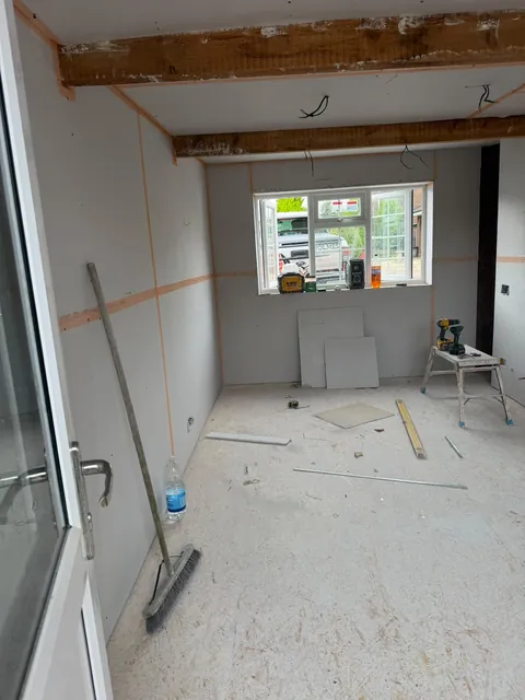 Walls and ceiling covered in plasterboard, with the joints taped and tools on the floor.