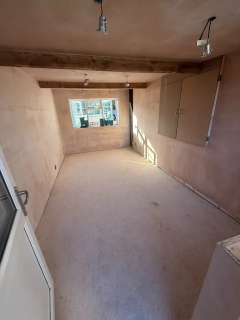The room after plastering, with exposed timber beams and a fitted cupboard.