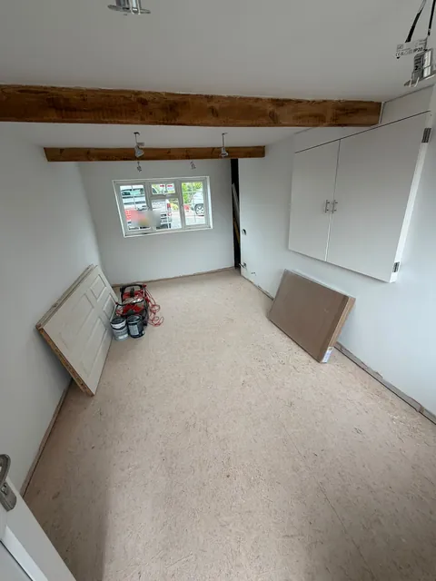 The room with walls painted white, before the floor covering was laid.