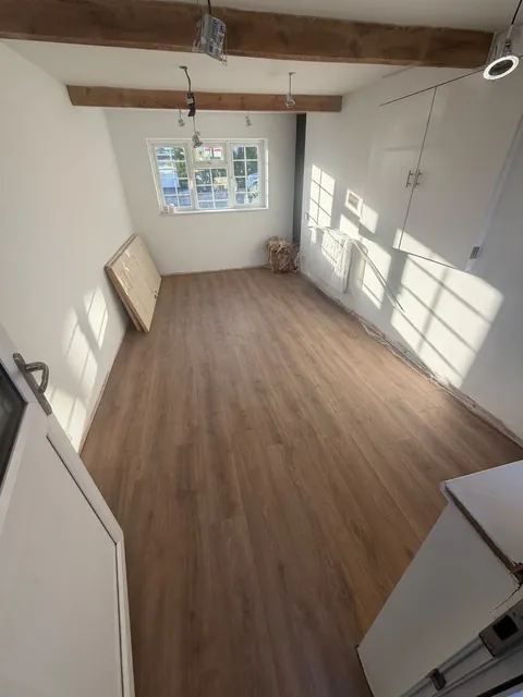 The room with wood-effect flooring laid; a door and radiator are still waiting to be fitted.