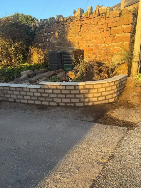 The new curved garden wall seen from the other end, in low evening sun.