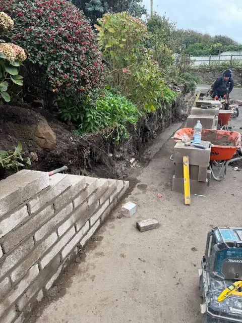 The wall under construction, with tools and materials on the path.