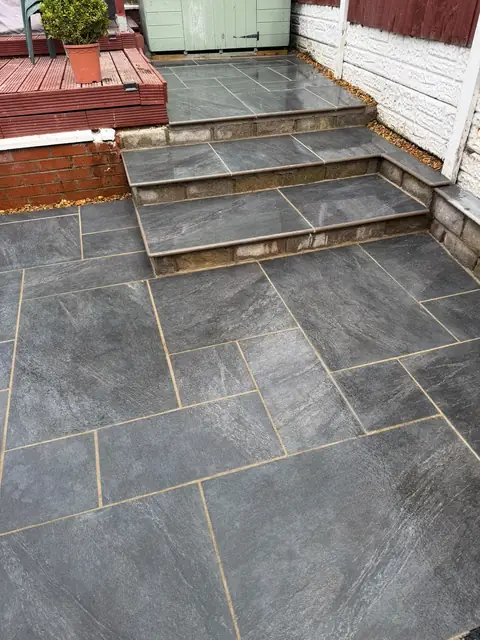 Dark grey patio with two wide steps rising to a raised paved level.