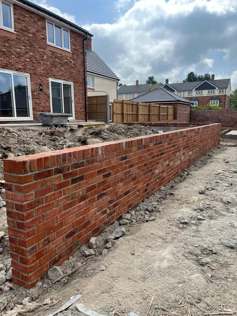 A long run of the finished red brick wall with a brick-on-edge top.