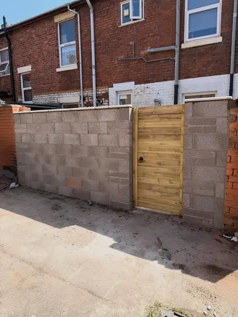 New block boundary wall with a timber gate set into it.