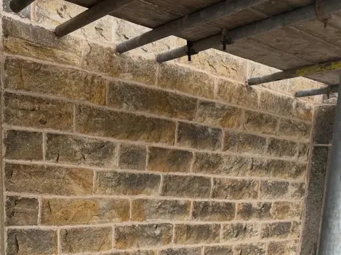 Close view of a sandstone wall with fresh, light-coloured mortar joints.