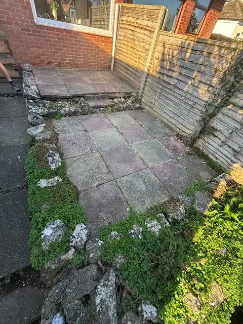 Old, uneven paving in a small garden beside the house.
