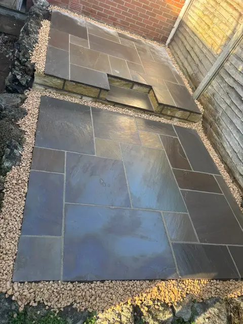 Dark stone patio on two levels with a gravel edge.