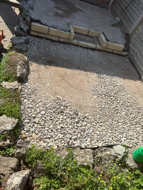 Crushed-stone sub-base spread across the area, with new walling at the far end.