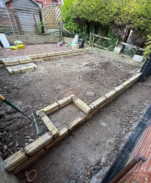 A garden cleared back during the work, with new stone walling forming two levels.