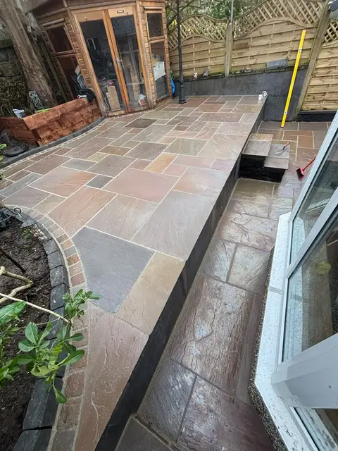 Finished two-level natural stone patio with steps, a cobble border and planting beds.