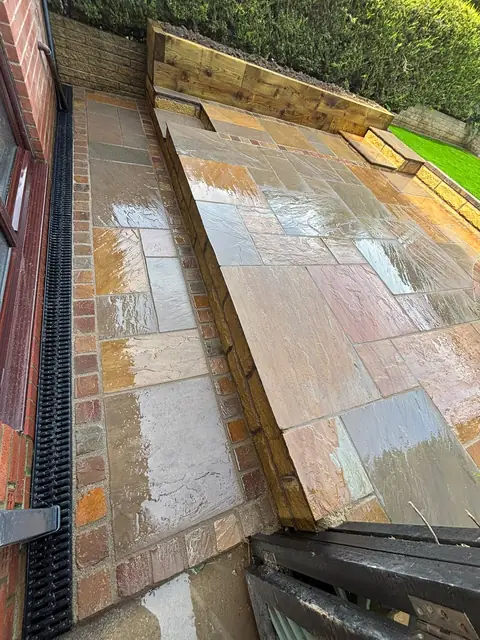Natural stone paving on two levels, with a channel drain along the house wall.