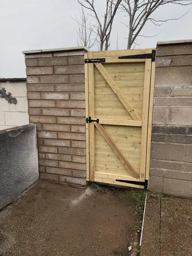 New timber garden gate hung between a brick pier and block wall