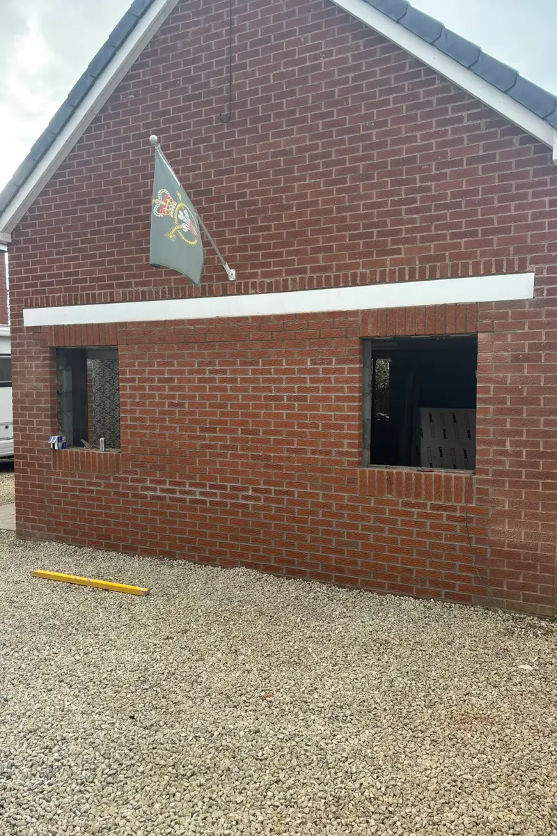The same garage front bricked up in matching red brick, with two new window openings.
