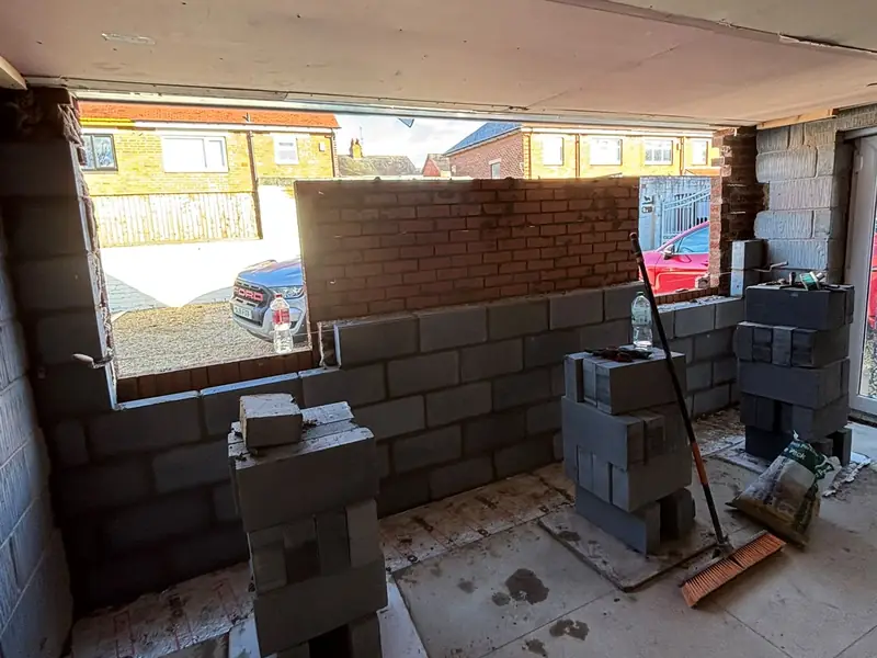 Inside a garage during a conversion, with new blockwork being built across the former door opening.