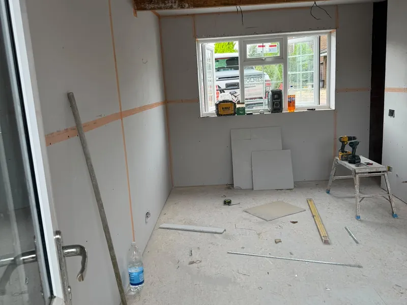 Garage walls and ceiling covered in plasterboard, with the joints taped and tools on the floor.