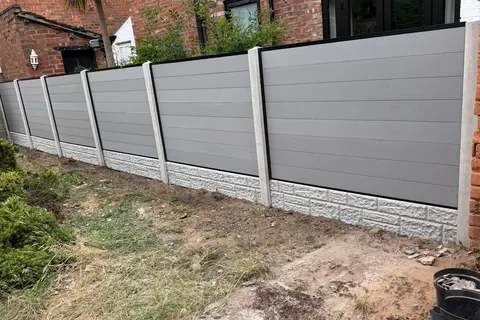 Grey slatted fence panels set between concrete posts along a garden boundary.
