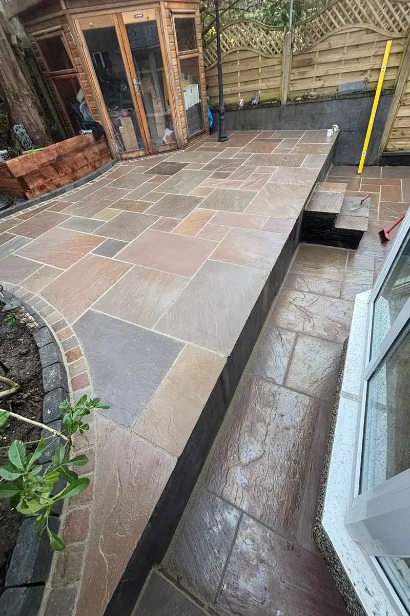 The finished two-level garden with natural stone paving, steps, a cobble border and planting beds.