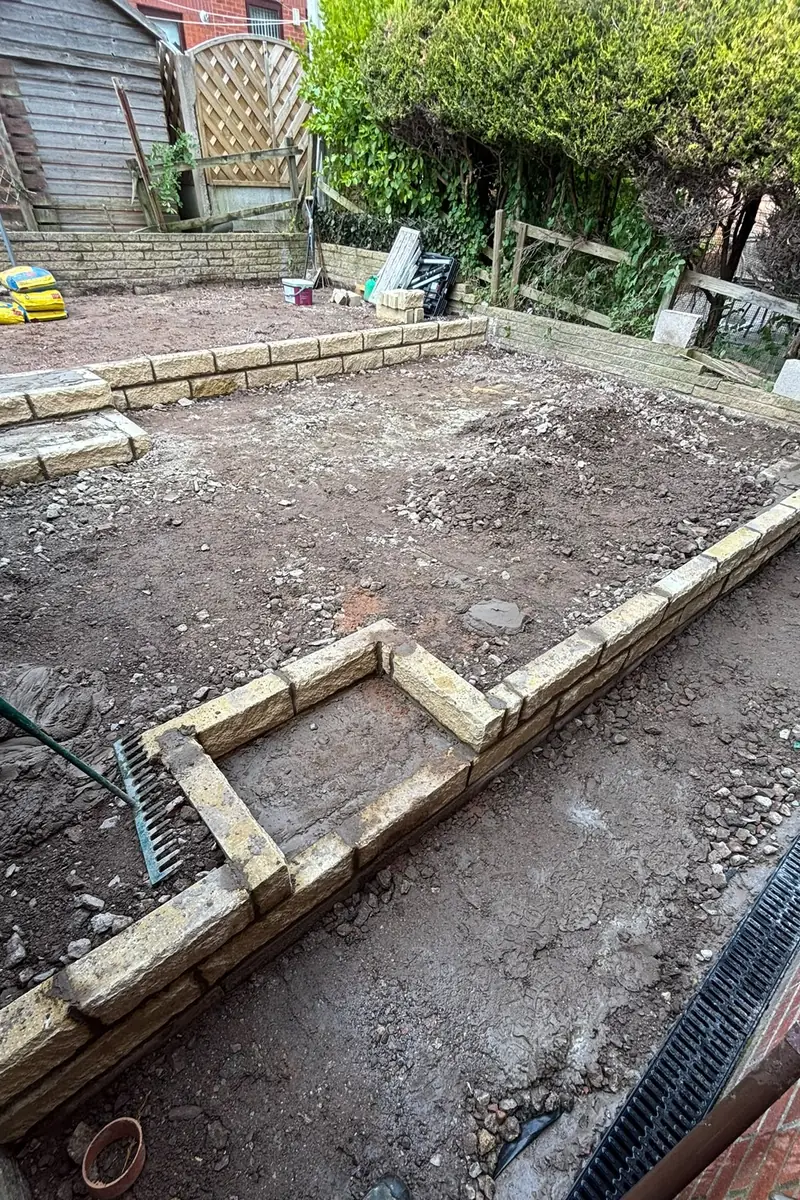 A garden cleared back during the work, with new stone walling forming two levels.