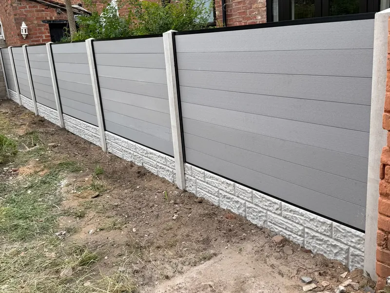 A long run of grey slatted fence panels set between concrete posts, on decorative concrete gravel boards.