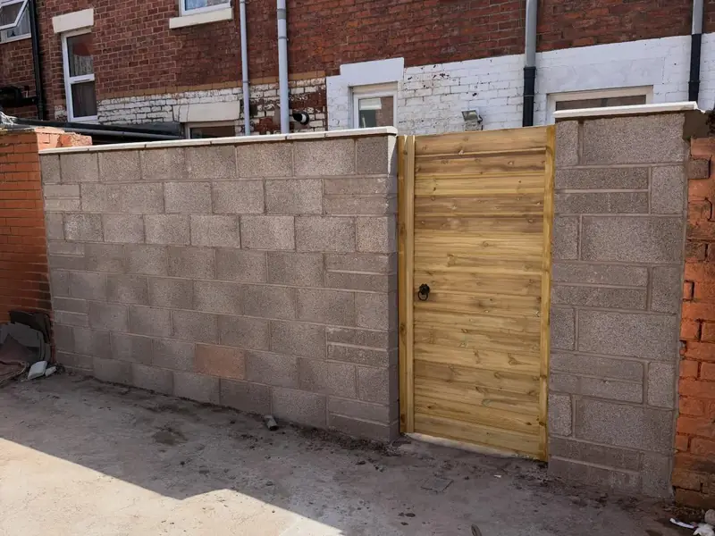 New block boundary wall with a timber gate set into it.