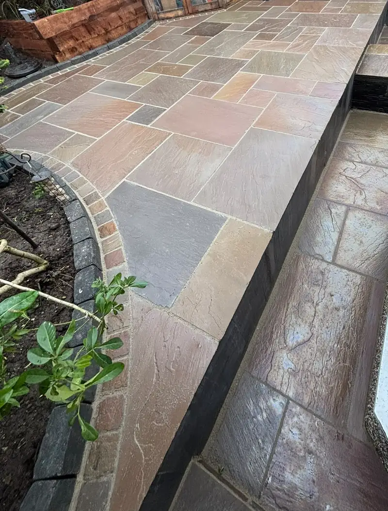 Finished two-level natural stone patio with steps, a cobble border and planting beds