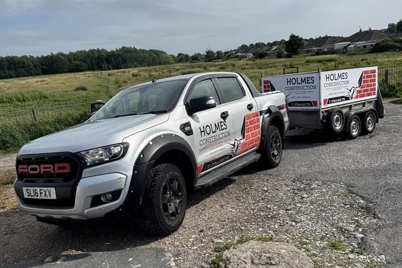 Holmes Construction branded pickup truck and trailer.