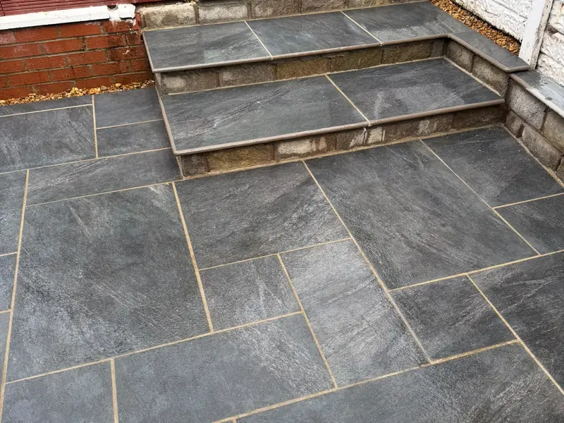 Dark grey patio with two wide steps rising to a raised paved level.