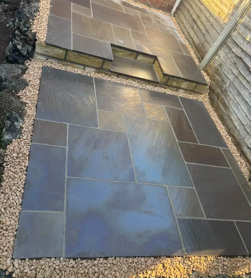 Dark natural stone patio on two levels with a gravel edge